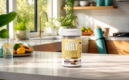 Whey Gummy RAVU sabor banoffee em cenário de cozinha ensolarada com frutas e rotina leve