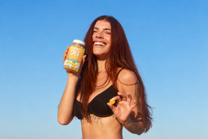 Mão abrindo pote de Creatina RAVU na praia